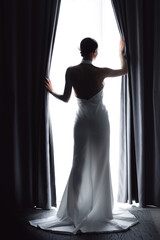 Portrait Bride woman in Silhouette Against Window Light in Elegant Wedding Dress, modern fashion...