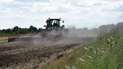 Fototapeta premium Kyiv, Ukraine. tractor in a field, tractor with a plow on an agricultural field. big green tractor working in the field, soil preparation, harvesting, business, agriculture.
