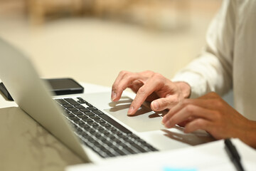 Businessman typing at laptop keyboard browsing internet or searching information