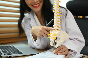 Physiotherapist showing a lumbar disc herniation with a spinal model while giving consultation at rehab clinic