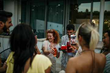 Cute diverse friends making surprise for excited birthday lady, holding birthday cake and smiling