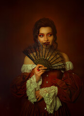 Obraz premium Art portrait Gothic Fantasy Woman queen holding in hands black lace fan hides face. dark hair high bun. Vintage white red dress. Happy girl vampire teeth evil cruel sexy smiling face lips sharp fangs