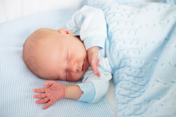 Newborn baby boy in white bassinet