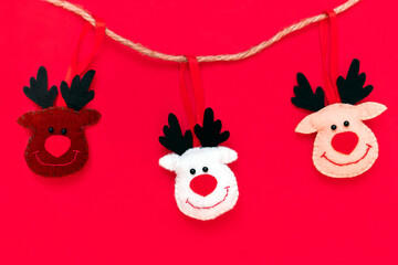 Toy Deers hanging on a rope isolated on the red background with copy space. The atmosphere of Christmas and New Year. Christmas banner, mock-up