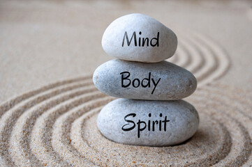 Mind, body and soul text on zen stones with sand background