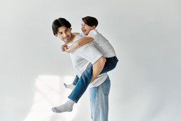 A father gives his son a piggyback ride in a white room.