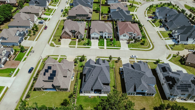 Quiet residential street in upscale new development neighborhood row of expensive two-story houses solar roof panel, Dallas suburbs, sustainable modern Texas custom homes in Flower Mound, aerial