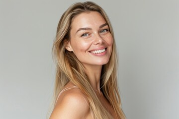 Naklejka premium Female portrait with smile, makeup, and natural attractiveness on grey studio background. Woman, lady, and makeup for confidence, face cleanse, and organic facial.