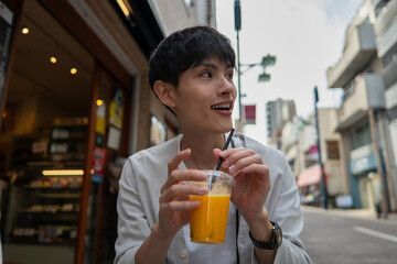 店先でオレンジジュースを飲む男性