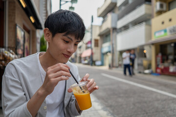 店先でオレンジジュースを飲む男性