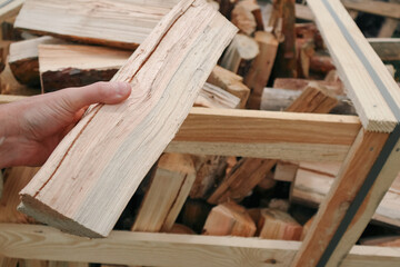 A man holding firewood log in his hand. Firewood for the fireplace. Pallet of firewood.