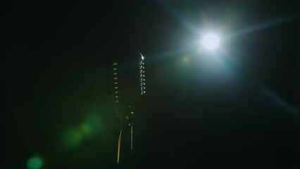 Retro microphone close-up in dark hall in light of spotlight. Professional equipment for music events