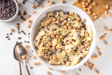 Bowl with vegan Chickpea raw Cookie dough, sweet alternative vegetarian dessert made from Chickpea and chocolate chips. on kitchen table with ingredients