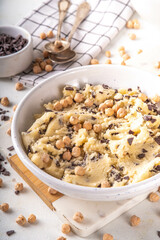 Bowl with vegan Chickpea raw Cookie dough, sweet alternative vegetarian dessert made from Chickpea and chocolate chips. on kitchen table with ingredients