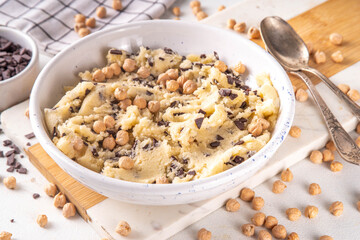 Bowl with vegan Chickpea raw Cookie dough, sweet alternative vegetarian dessert made from Chickpea and chocolate chips. on kitchen table with ingredients