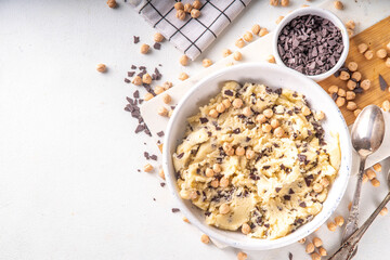 Bowl with vegan Chickpea raw Cookie dough, sweet alternative vegetarian dessert made from Chickpea and chocolate chips. on kitchen table with ingredients