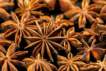Anise stars texture background, above view close up flavor spices dried anise seeds on dark, still life with natural condiments, aromatic ingredient for cooking drink and food