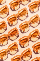Pattern of Trendy sunglasses with Yellow Frame on peach background, beach vibes, summertime mood,...