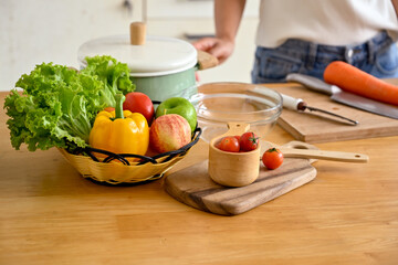 Close-up of a woman arranging a basket of salad vegetables and fruits in the kitchen island, making her healthy breakfast. home cooking, domestic life, healthy lifestyl