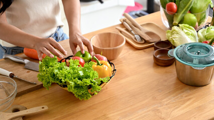 Close-up of a woman arranging a basket of salad vegetables and fruits in the kitchen island, making her healthy breakfast. home cooking, domestic life, healthy lifestyle