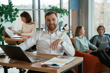 Obraz premium By the table with laptop. People are working in the office with bean bags chairs in it