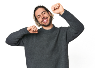 Young Caucasian man in studio setting celebrating a special day, jumps and raise arms with energy.