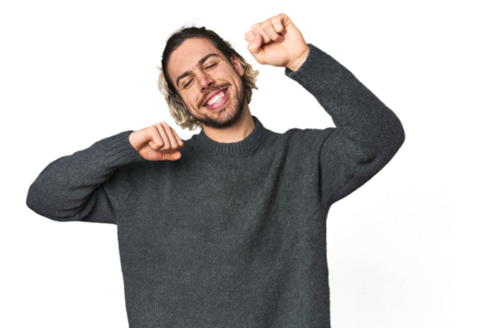Young Caucasian man in studio setting celebrating a special day, jumps and raise arms with energy.
