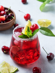 Cherry-lime mojito cocktail with mint, lime and ice on a light background with fresh berries close up.