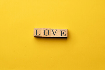 a yellow warm background without shadows wooden cubes with black letters laid out word love