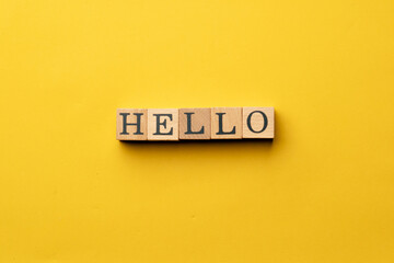 a yellow warm background without shadows wooden cubes with black letters laid out word hello