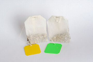 Two tea bags with empty labels of different colors on a white background. Template with blank tag on the theme of hot soft drinks.