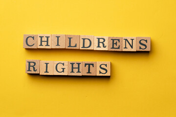 a yellow warm background without shadows wooden cubes with black letters laid out word childnrens rights