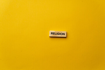 a yellow warm background without shadows wooden cubes with black letters laid out word religion