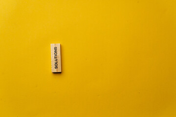 a yellow warm background without shadows wooden cubes with black letters laid out word solutions