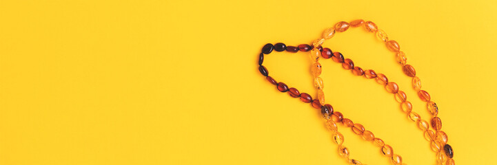 Banner with amber beads laid on a yellow background.