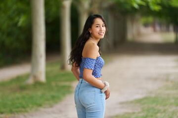 A woman in a blue shirt and blue jeans is smiling and posing for a picture