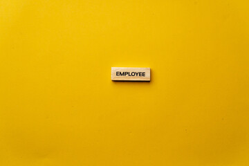 a yellow warm background without shadows wooden cubes with black letters laid out word employee