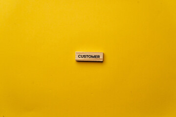 a yellow warm background without shadows wooden cubes with black letters laid out word customer
