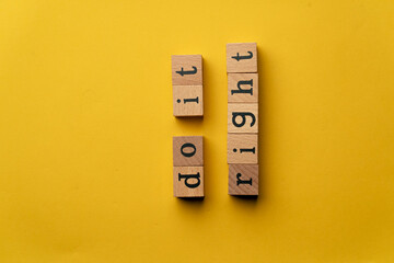 a yellow warm background without shadows wooden cubes with black letters laid out word do it right