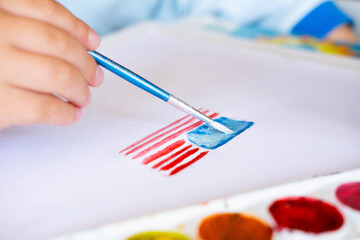 The American 4th of July flag is painted with watercolors by a child's hand. Patriotism,...
