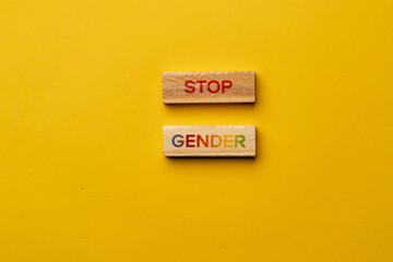 a yellow warm background without shadows wooden cubes with black letters laid out word stop gender