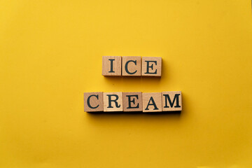 a yellow warm background without shadows wooden cubes with black letters laid out word ice cream