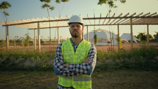 Portrait professional Caucasian male man builder guy businessman eco engineer repairman in hard hat helmet uniform posing crossing hands specialist worker crossed arms outside park construction meadow