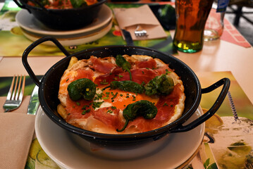 Plat typique de la cuisine espagnole avec de œufs frits, du jambon ibérique, des petits poivrons verts cuits et des pommes de terre