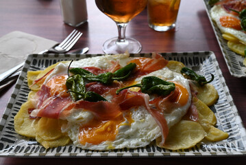 Plat typique de la cuisine espagnole avec de œufs frits, du jambon ibérique, des petits poivrons verts cuits et des pommes de terre