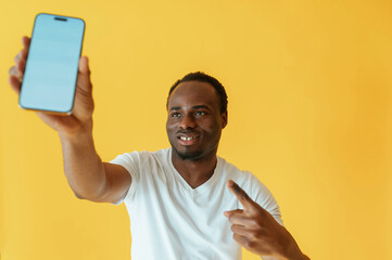 Empty display of smartphone, holding. Black man is in the studio against yellow background