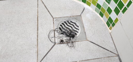 Woman hair fell at the drain pipe in the bathroom. A lot of black hair  clump clogged the mouth of the drain. Problems with clogged water pipes. Problems with scalp health. sewerage
