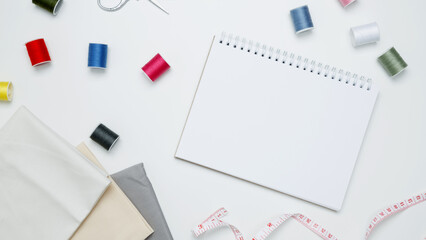 Composition with various threads and sewing accessories on white background. Mock up notebook