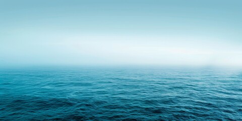 Obraz premium The image shows a calm sea with a clear horizon. The water is a deep blue color and the sky is a light blue color.