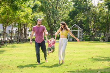 Fototapeta premium Happy family walking and playing together in garden. little children with parents are free and active people in nature. Feeling of fun and enjoyment concept. Family day.
